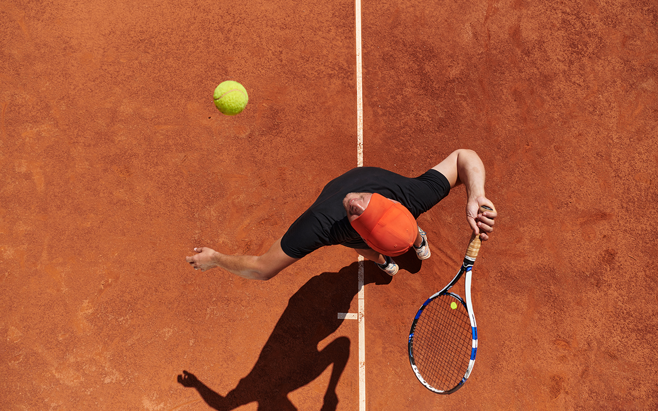 Tennisspieler beim Aufschlag auf einem Sandplatz aus der Vogelperspektive, SV Walpertskirchen Tennis.